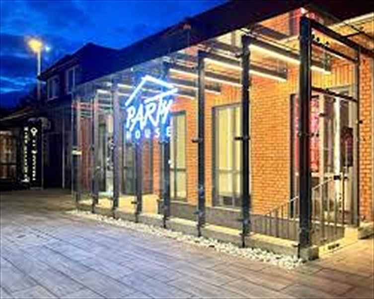 Party House z zewnątrz — wejście z neonem nocą